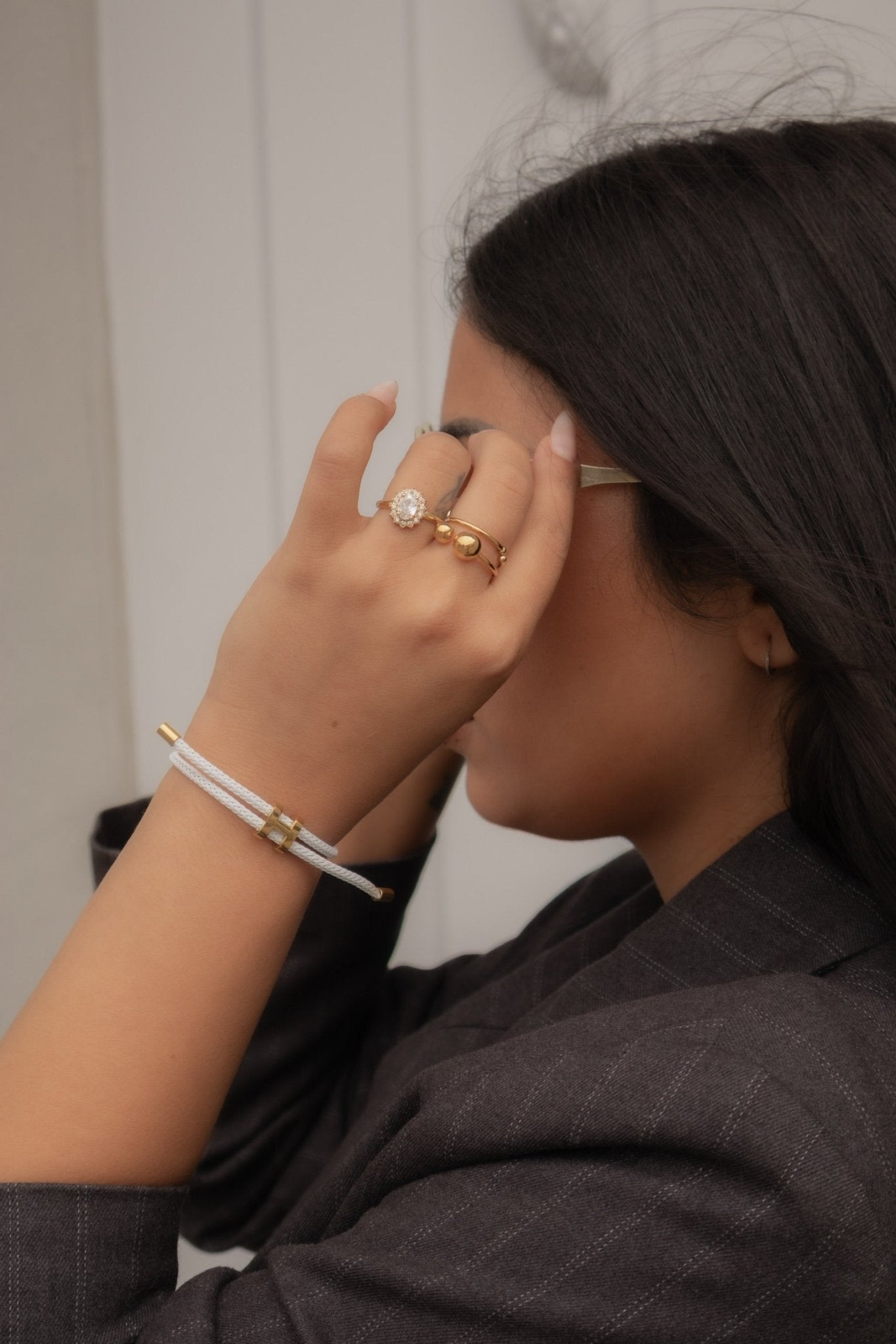Bracelet doré Héris en cordon tressé blanc, porté au poignet, main près du visage