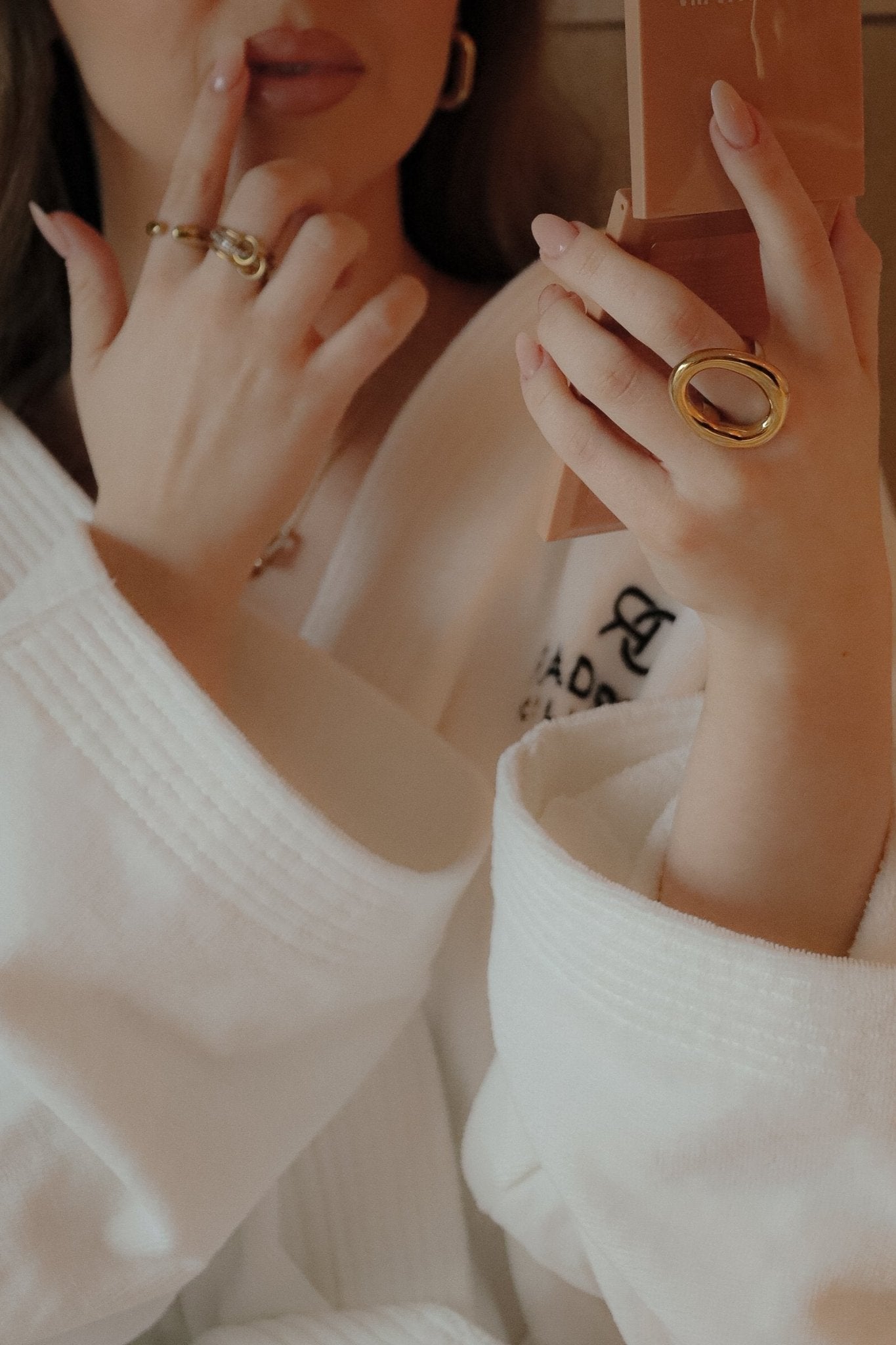 Femme portant un peignoir, touchant ses lèvres du doigt et portant une bague dorée