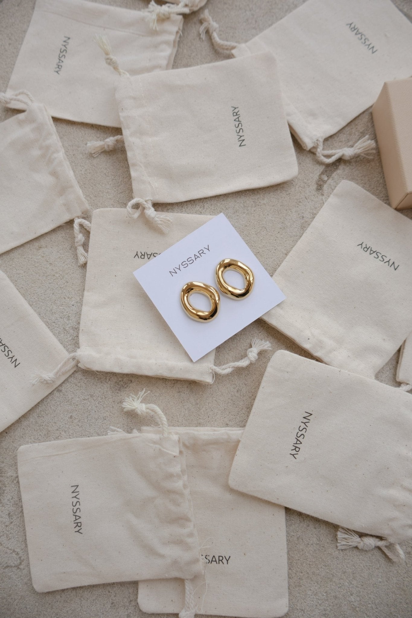 Boucles oreilles femme Alis ajourées, présentées sur des pochettes Nyssary