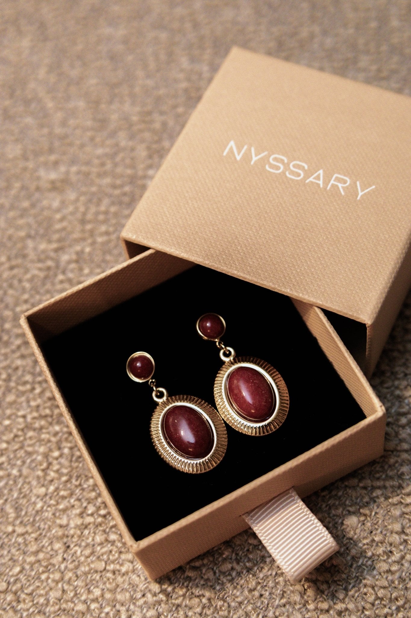 Boucles oreilles dans une boîte avec l’inscription « Nyssary »