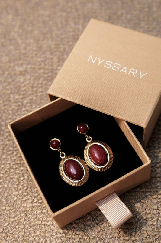 Boucles oreilles dans une boîte avec l’inscription « Nyssary »