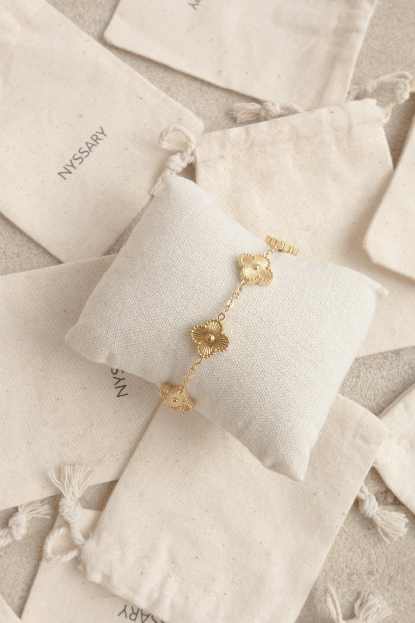 Bracelet doré avec motif tréfle présenté sur coussin bijou