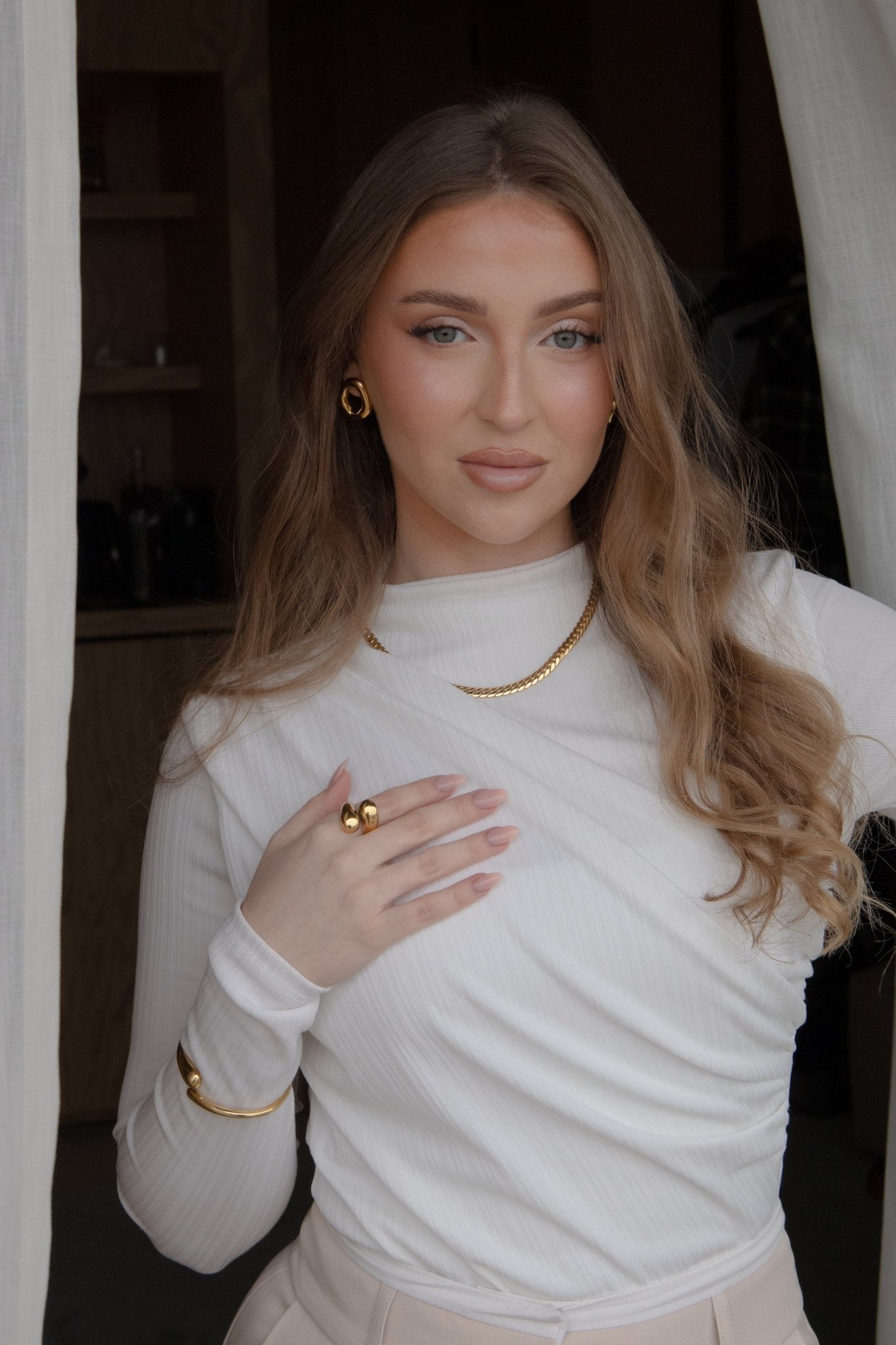 Femme portant un collier femme doré, la main posée sur sa poitrine